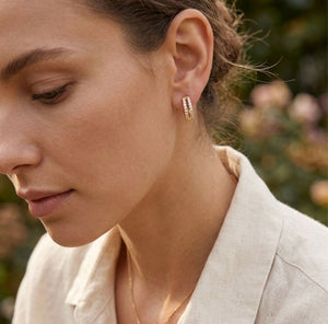 Woman wearing gold split band crystal huggie hoop earrings lifestyle shot elegant gold jewellery UK The Colourful Aura