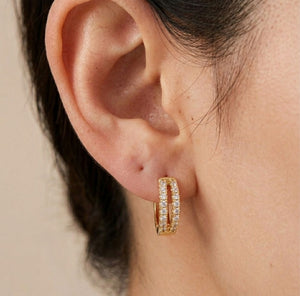 Close-up detail of gold split band crystal huggie hoop earring worn on ear dual crystal rails open centre