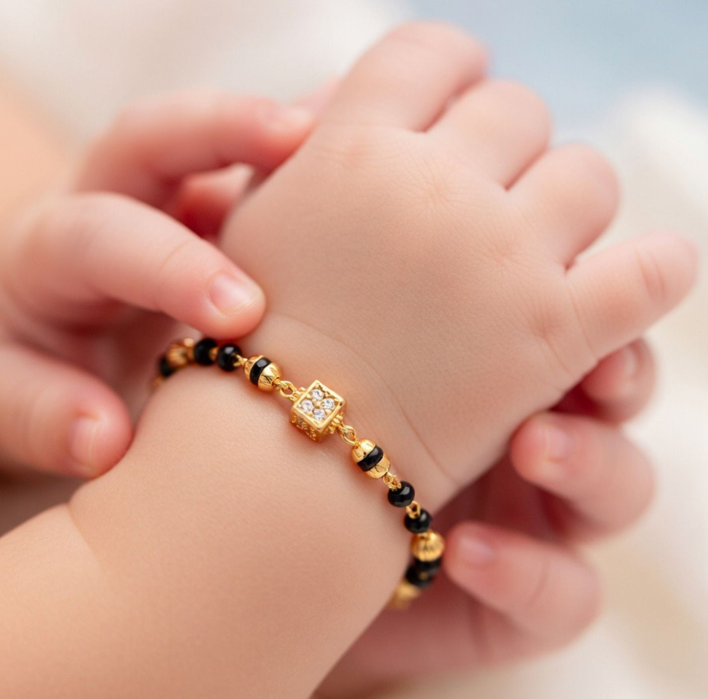  3Smiling baby wearing Nazaria black bead gold bracelet Indian evil eye protection new baby gift UK