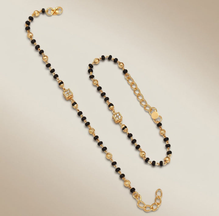 Baby Nazaria black bead gold bracelet flat lay showing full length infinity clasp and extension chain