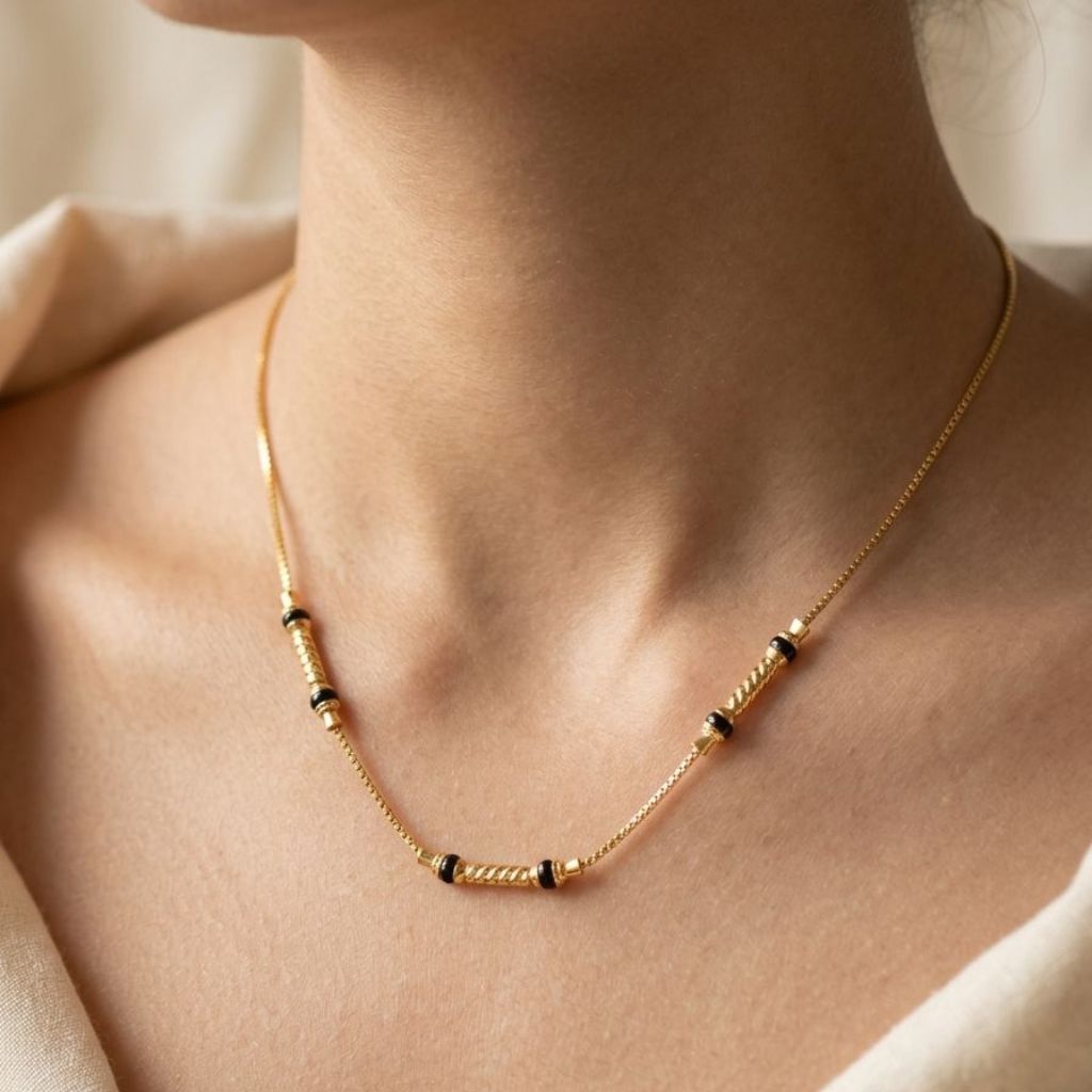 Close-up of a minimalist 18ct gold plated black bead chain necklace worn on a woman's neck