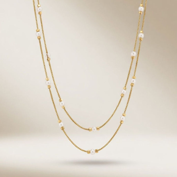 Full length view of an 18ct gold plated double strand imitation pearl and gold bead necklace on a neutral background