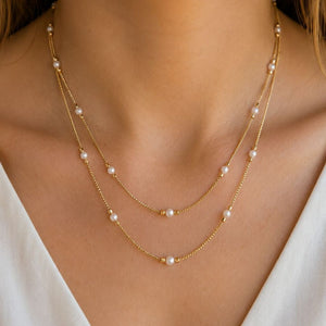 Front view of a woman wearing an 18ct gold plated double strand imitation pearl necklace with a white top