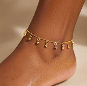 Woman wearing gold ball charm anklet on ankle lifestyle shot Indian boho jewellery UK The Colourful Aura