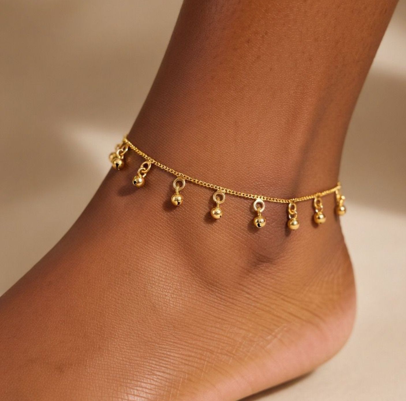 Woman wearing gold ball charm anklet on ankle lifestyle shot Indian boho jewellery UK The Colourful Aura