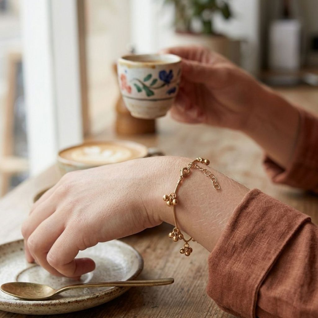Close-up of a woman's wrist wearing an 18ct gold plated ball cluster charm bracelet with adjustable clasp