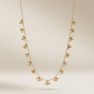 Full length view of an 18ct gold plated brass necklace with dangling ball cluster charms on a neutral background