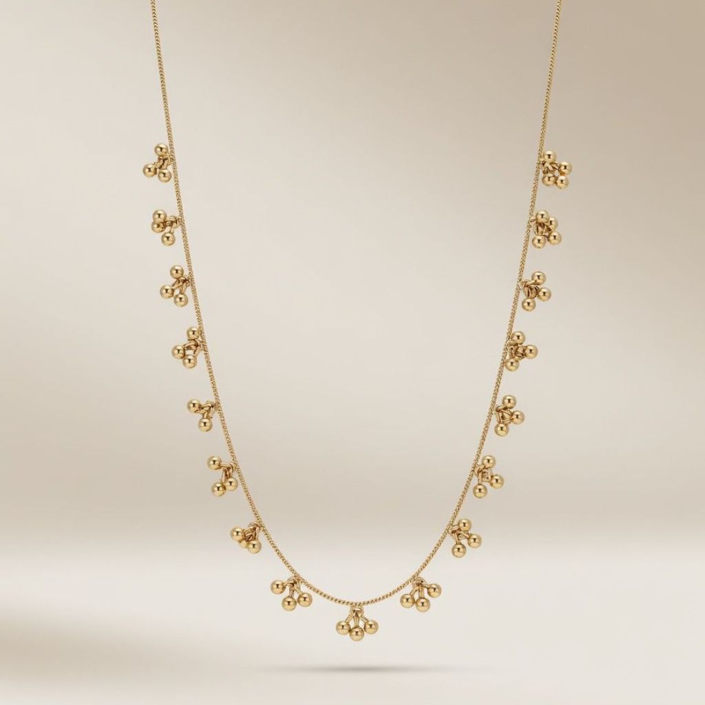 Full length view of an 18ct gold plated brass necklace with dangling ball cluster charms on a neutral background