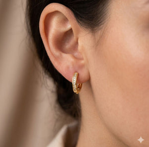 Close-up detail of gold crystal huggie hoop earring worn on ear brass channel set stones