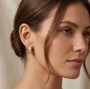 Close-up detail of gold double row pavé crystal huggie hoop earring worn on ear milgrain gold setting