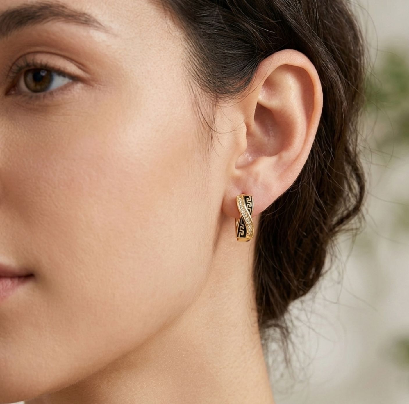 Woman wearing gold Greek key crossover huggie hoop earrings lifestyle shot ethnic jewellery UK The Colourful Aura