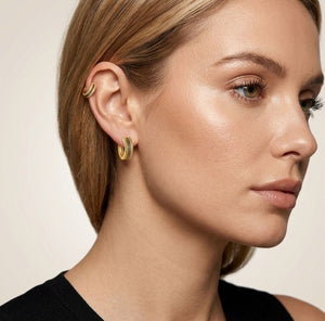 Woman wearing gold Greek key crystal huggie hoop earrings lifestyle shot gold jewellery UK The Colourful Aura
