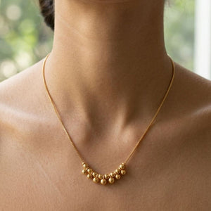 Gold plated cluster ball bead statement necklace worn by model close up view