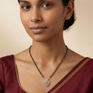 Close up of gold plated mangalsutra with CZ crystal heart pendant worn by model in saree