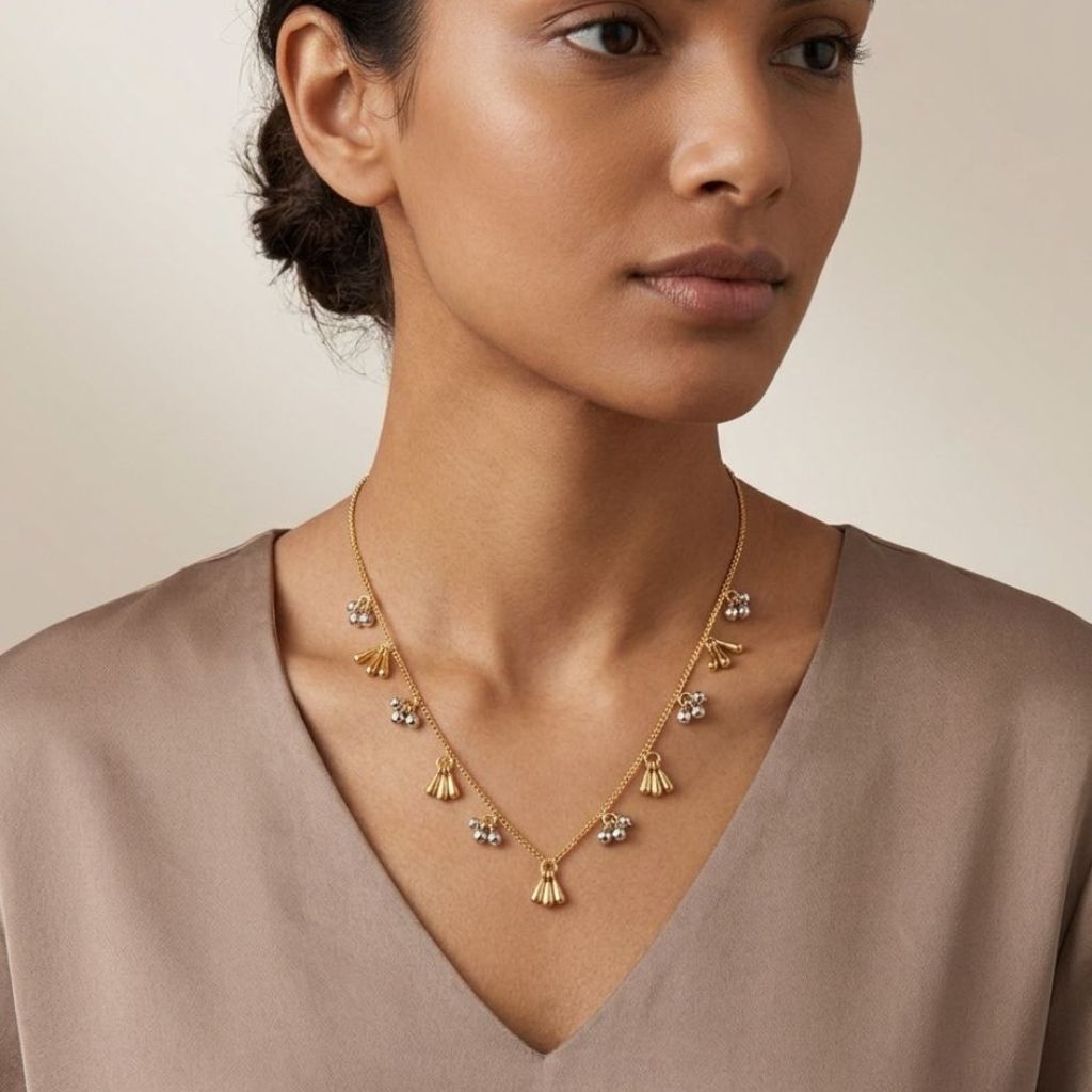 Gold plated dual tone tassel and silver ball charm necklace worn by model side profile view