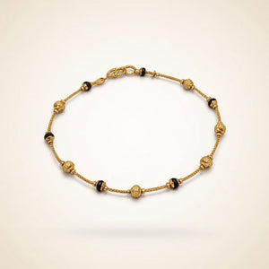 Gold plated mangalsutra bracelet with ornate filigree ball beads and black bead accents flat lay