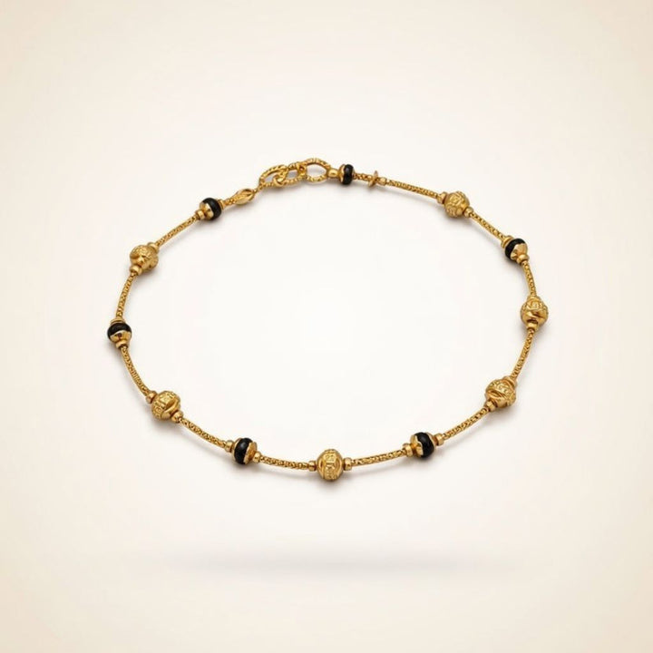 Gold plated mangalsutra bracelet with ornate filigree ball beads and black bead accents flat lay