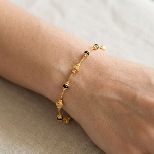 Close up of gold plated mangalsutra filigree ball bracelet with black beads worn on model wrist
