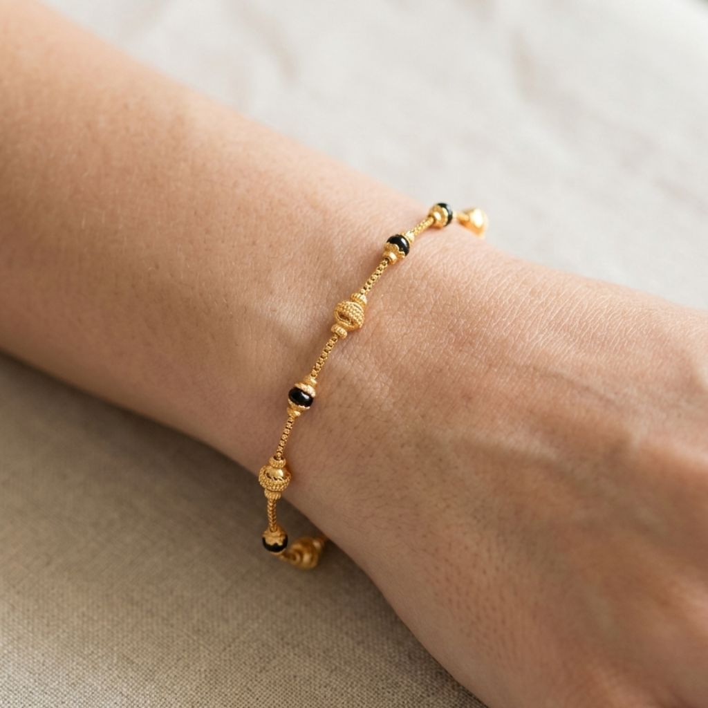 Close up of gold plated mangalsutra filigree ball bracelet with black beads worn on model wrist