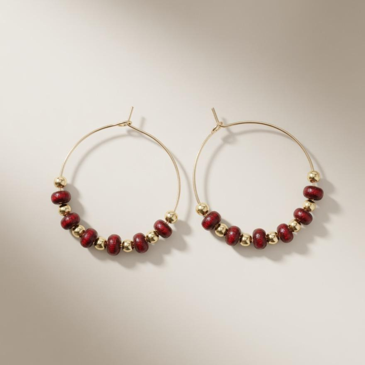 Pair of 30mm gold plated hoop earrings with red sandalwood and gold beads on a neutral background
