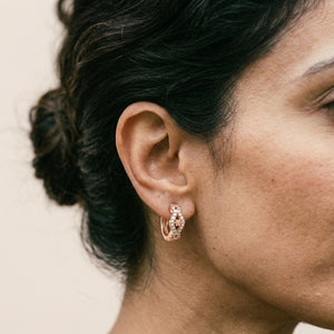 Close-up of rose gold crystal huggie hoop earrings with pave CZ floral motif — boho earrings UK
