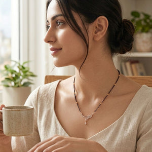 Model wearing rose gold mangalsutra with CZ teardrop pendant holding coffee cup lifestyle shot